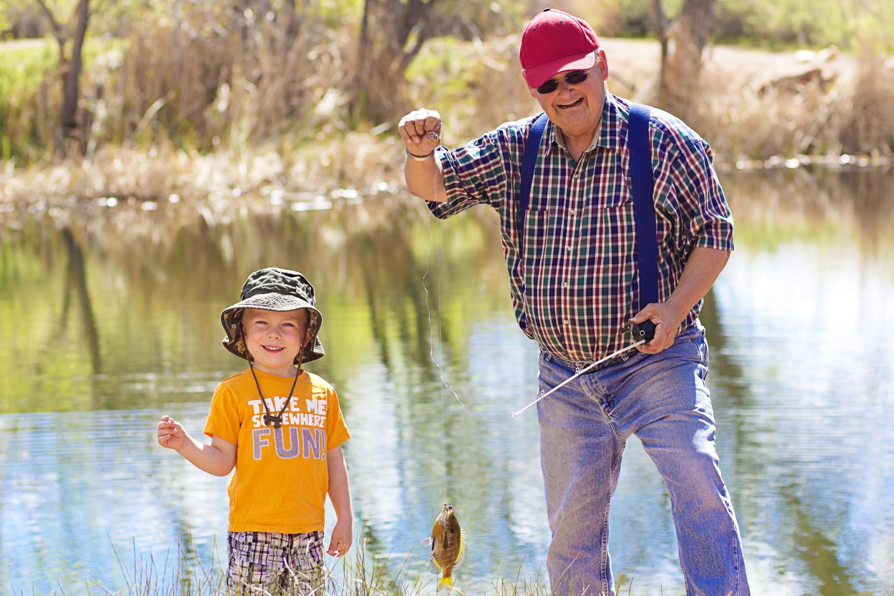 Little boy and his grandfather catching a fish